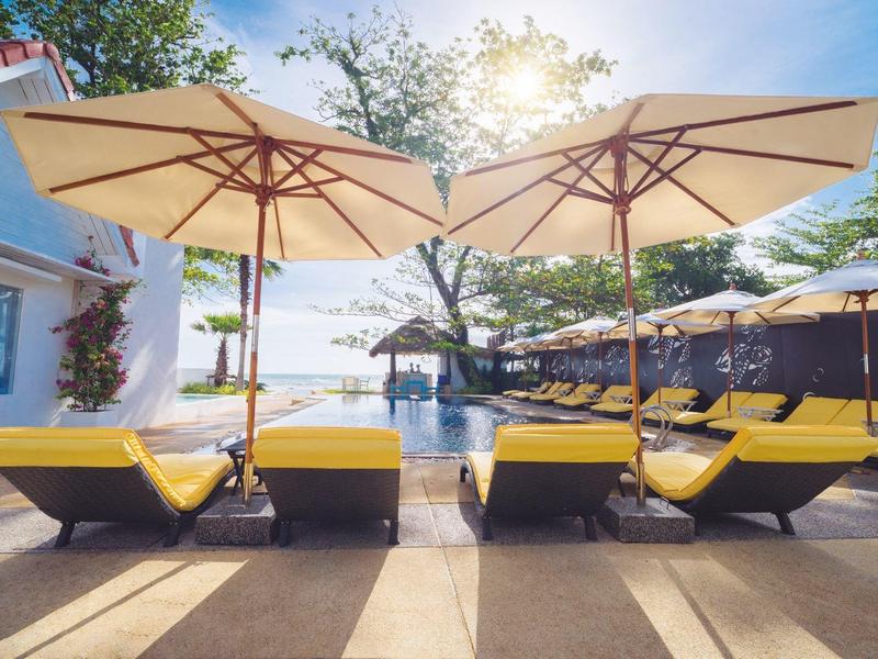 Poolbereich mit gelben Liegen und großen Sonnenschirmen an einem sonnigen Tag