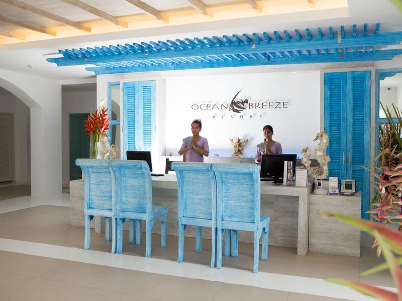 Heller Empfangsbereich mit blau gestrichenen Möbeln und zwei Mitarbeitern an einem Tresen.