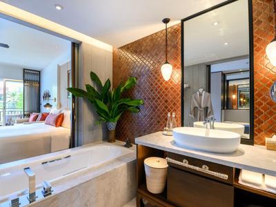 Modernes Badezimmer mit Badewanne, Waschtisch und Akzentwand in Rot-Orange mit Pflanzen.