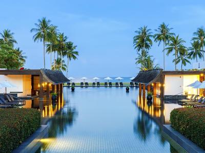 Luxuriöser Infinity-Pool mit Blick auf das Meer, umgeben von Palmen und modernen Liegen.