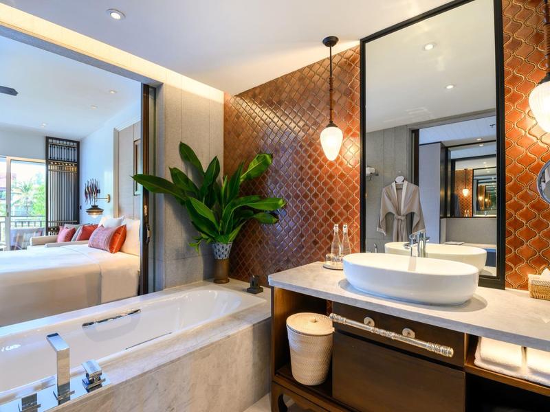 Modernes Badezimmer mit Badewanne, Waschtisch und Akzentwand in Rot-Orange mit Pflanzen.