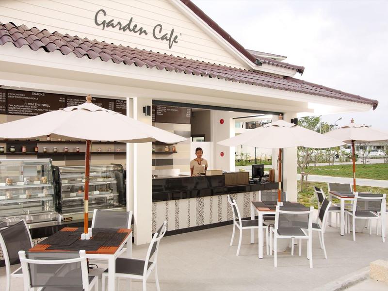 Außenbereich eines Cafés mit weißen Tischen, Stühlen, Sonnenschirmen und Buffet-Theke.