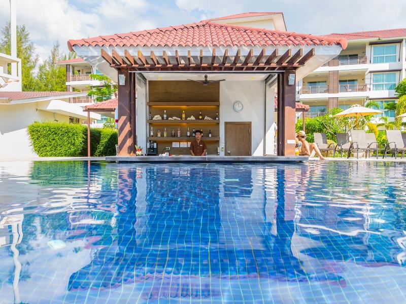 Moderner Pool mit blau gekacheltem Becken und offener Poolbar mit Holzdach bei Sonnenschein.