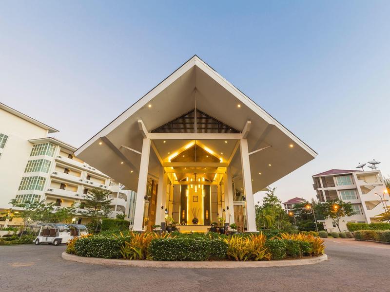 Ehemaliges luxuriöses Lobbygebäude mit Glas und Holz, umgeben von Grünflächen und Wohnungen.
