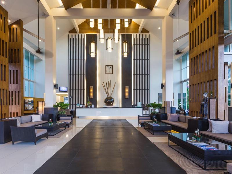 Große, moderne Hotellobby mit hohen Decken, Sitzbereichen und einem zentralen schwarzen Teppich.