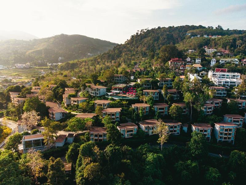 Colline illuminate dal sole con molte case e verde lussureggiante nel pomeriggio.