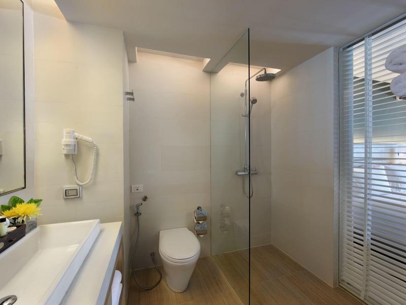 Bagno moderno con doccia in vetro, WC e lavabo con specchio e asciugacapelli.