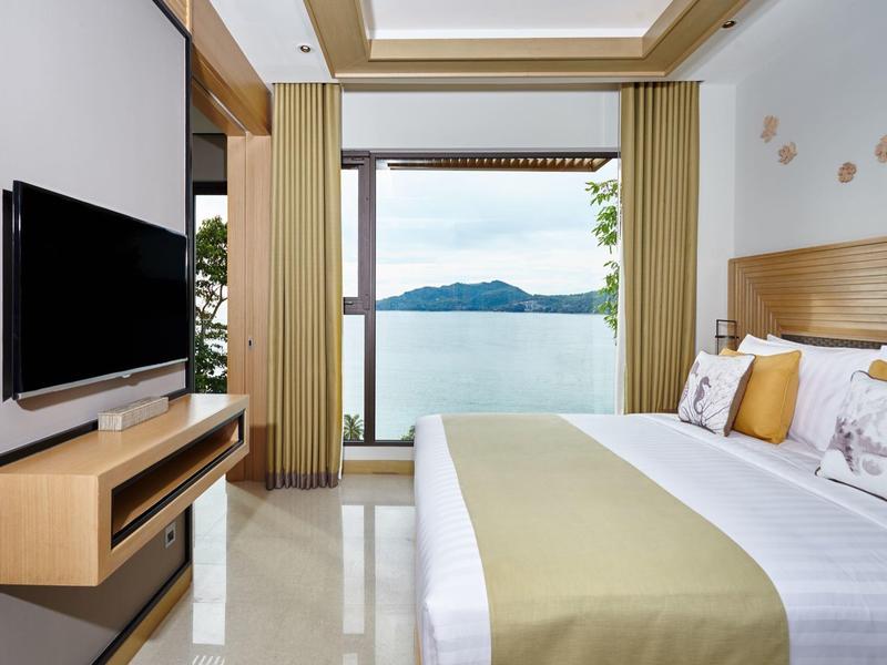 Camera d'hotel moderna con letto matrimoniale e vista sul lago e sulle montagne attraverso grandi finestre.