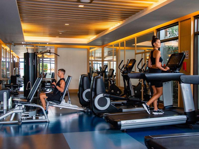 Palestra moderna dell'hotel con macchine cardio e persone che si allenano.