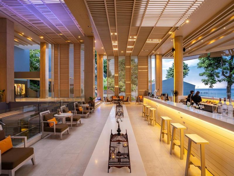 Ristorante d'hotel moderno con lungo bancone, posti a sedere e vista sul mare al crepuscolo.