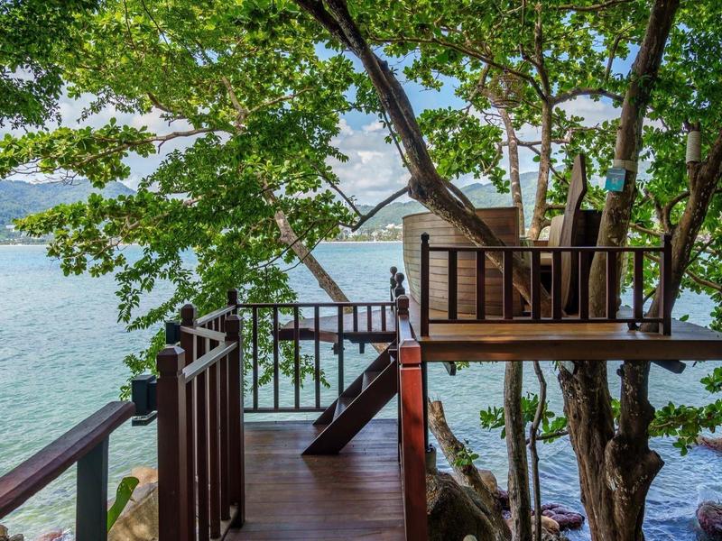 Piattaforma di casa sull'albero in legno con scale sopra acqua limpida e lago sullo sfondo