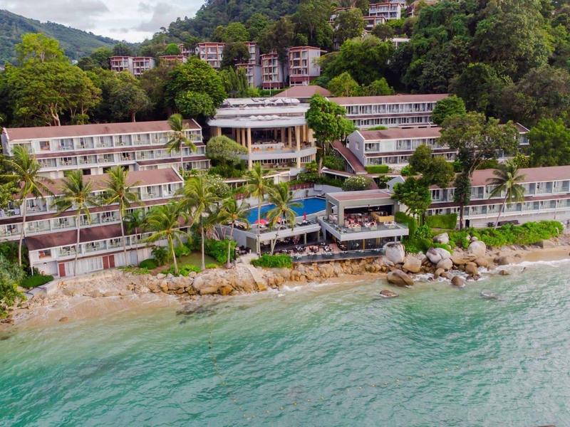 Resort alberghiero su una collina boscosa con vista su una spiaggia tropicale e mare turchese.