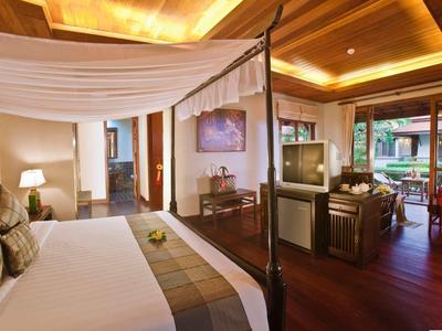 Luxuriöses Hotelzimmer mit Himmelbett, Sitzbereich und warmem Holzdekor.