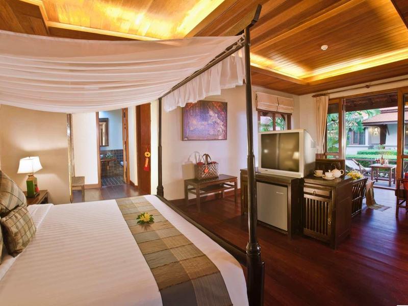 Luxuriöses Hotelzimmer mit Himmelbett, Sitzbereich und warmem Holzdekor.