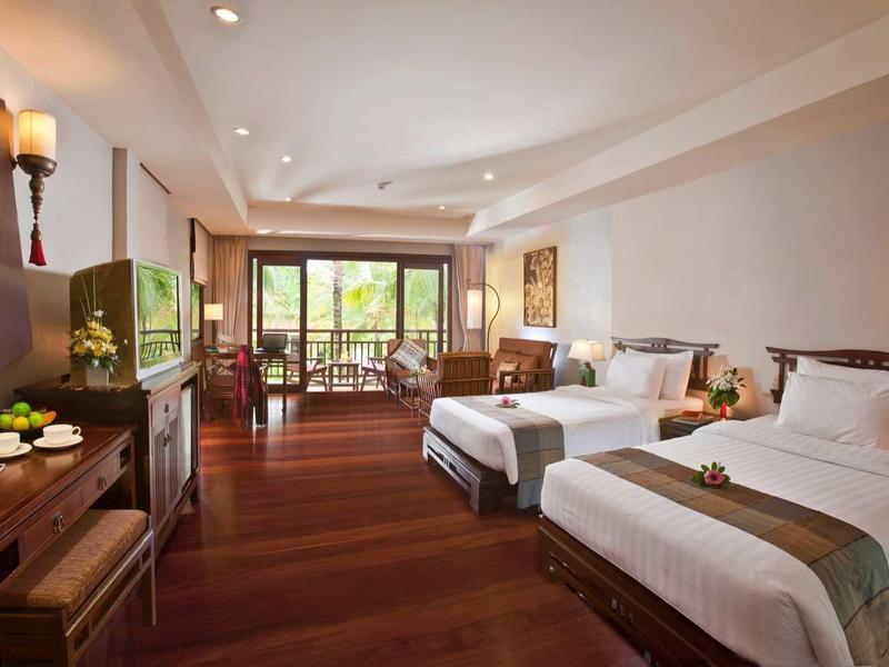 Großes Hotelzimmer mit zwei Betten, Holzboden und Balkon mit Blick ins Freie.