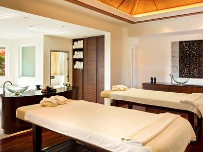 Salle de massage moderne avec deux tables et éclairage chaud.