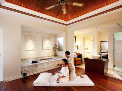 Deux femmes profitant d'un massage dans une salle de spa élégante avec un sol en bois et un éclairage doux.