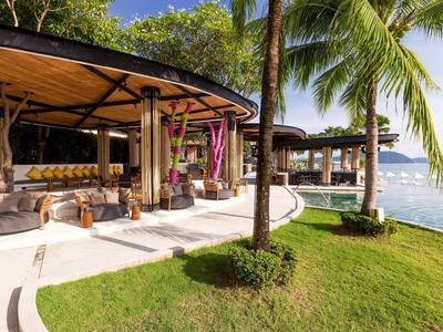 Luxuriöse offene Veranda mit moderner Einrichtung, Palmen und Blick auf das Meer bei Sonnenschein.