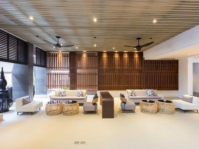 Espace lounge moderne avec panneaux en bois, fauteuils blancs et tabourets en rotin dans un hôtel.