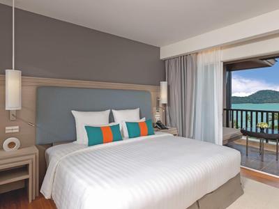 Chambre d'hôtel moderne avec grand lit, oreillers confortables et balcon avec vue sur les montagnes.