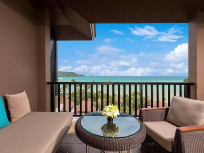 Balcon avec sièges et table donnant sur des terres vertes et un ciel bleu.