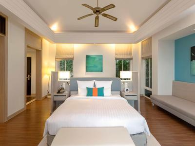 Chambre d'hôtel moderne avec grand lit, ventilateur de plafond et coin salon