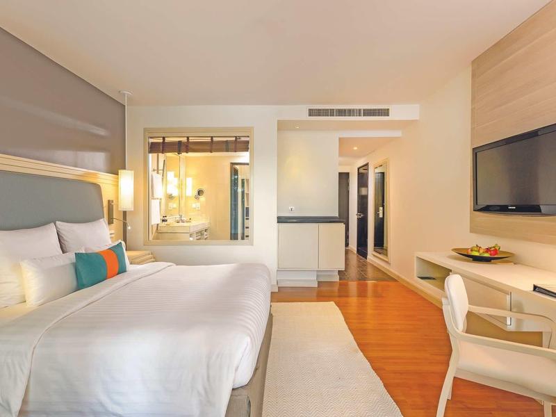 Modern ingerichte hotelkamer met groot bed, bureau en flatscreen-tv.