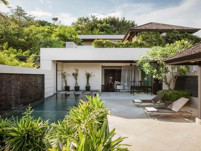 Bungalow moderno con piscina privata, lettini e verde rigoglioso.