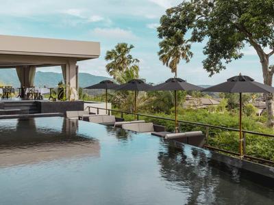 Piscina a sfioro moderna con ombrelloni scuri e palme in un ambiente tropicale dell'hotel.