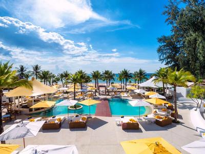 Grande piscina con lettini e ombrelloni in un resort tropicale sotto un cielo azzurro