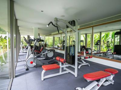 Palestra moderna con attrezzature e grandi finestre con vista sul verde.