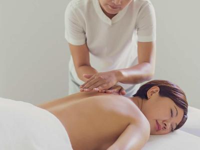 Donna che riceve un massaggio alla schiena in una stanza tranquilla e arredata di bianco.