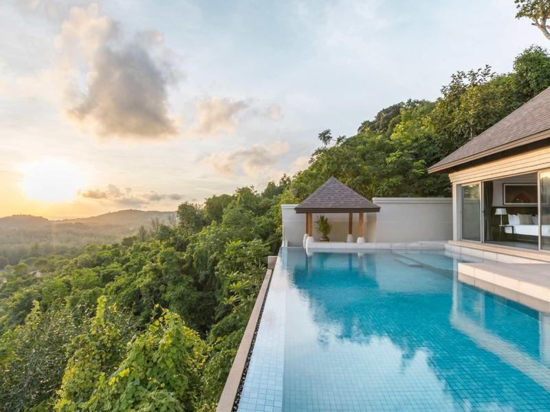 Piscina a sfioro con vista su colline boschive e tramonto.