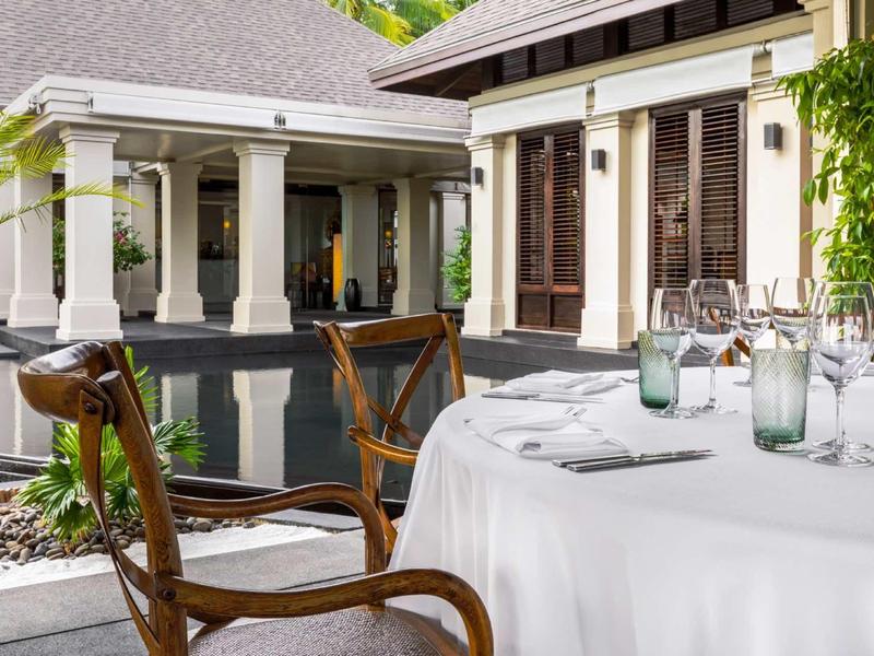 Elegante terrazza esterna con tavolo apparecchiato e piscina accanto a una casa con colonne.
