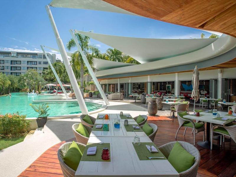 Area esterna moderna dell'hotel con piscina, tenda da sole e tavoli apparecchiati.