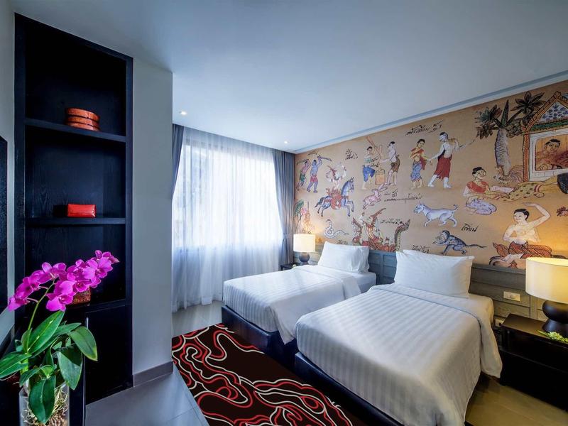 Camera d'hotel con due letti singoli, decorazione murale colorata e illuminazione moderna.