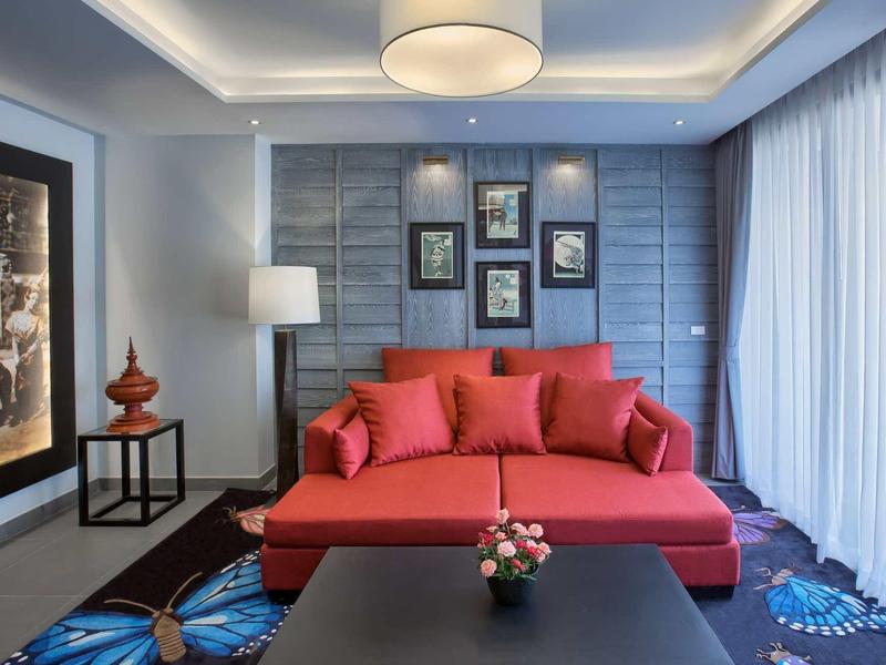 Soggiorno moderno con divano rosso e moquette blu in hotel.