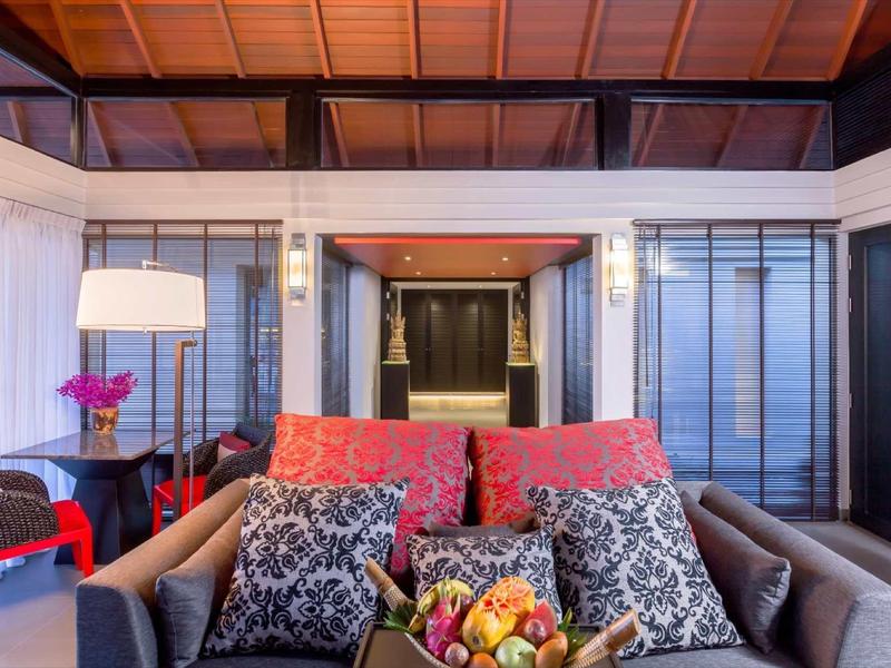 Moderna hall dell'hotel con divani accoglienti, cuscini colorati e una ciotola di frutta sul tavolo.