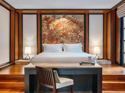 Piscina privada con tumbonas y casa tradicional tailandesa en un jardín tropical.