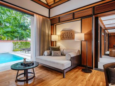 Casa con piscina en la orilla de un lago tranquilo, rodeada de árboles al atardecer.