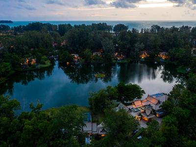 Vista nocturna de un lago tranquilo rodeado de casas iluminadas y árboles en una zona vacacional.