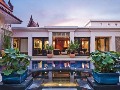 Patio de hotel con piscina, plantas en macetas y arquitectura moderna al atardecer
