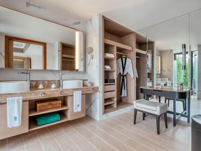 Baño moderno con lavabo doble, vestidor y banco.