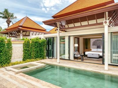 Bungalow moderno con piscina privada, puertas correderas abiertas y jardín tropical.