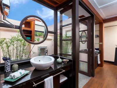 Baño moderno con espejo redondo, lavabo sobre encimera negra y grandes ventanas.