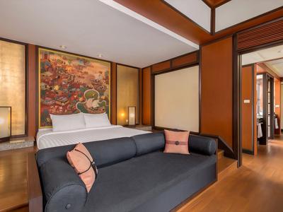 Habitación de hotel moderna con cama doble, sofá, cálidos detalles de madera e iluminación decorativa.