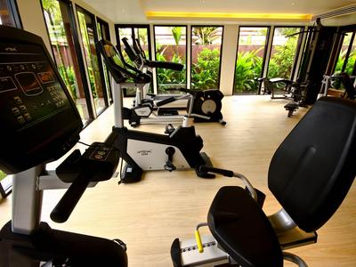 Licht fitnessruimte met moderne cardioapparaten en grote ramen met uitzicht op groen.