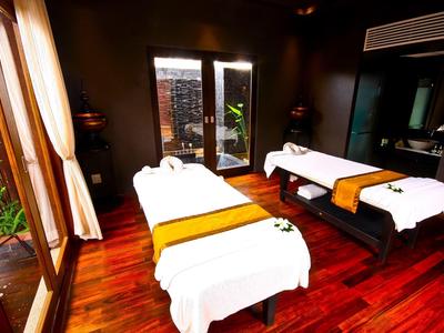 Spokojny pokój do masażu z dwoma stołami, drewnianą podłogą i dużymi oknami w strefie spa.