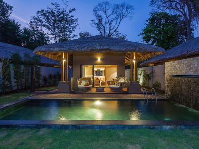 Wieczorny widok nowoczesnego domu z oświetlonym tarasem i basenem w ogrodzie.