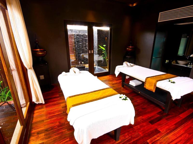 Spokojny pokój do masażu z dwoma stołami, drewnianą podłogą i dużymi oknami w strefie spa.